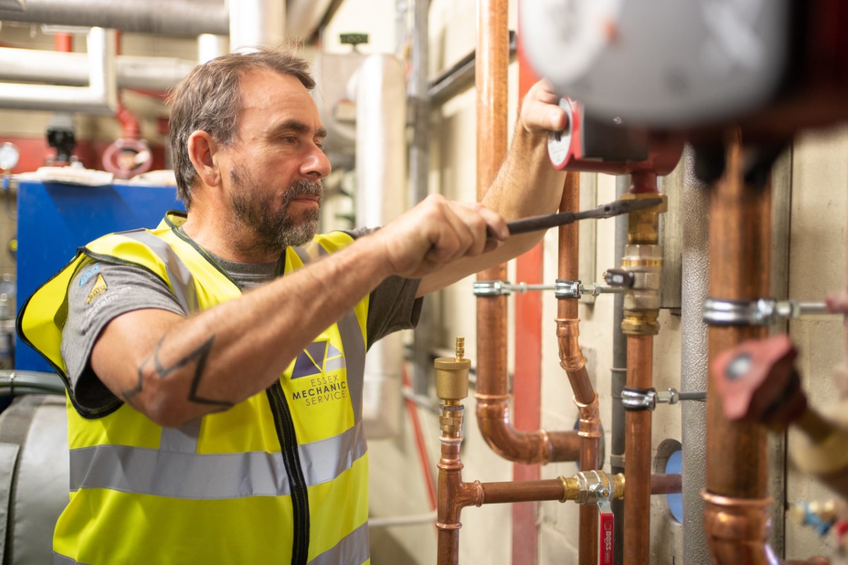 Worker using a spanner to loosen a pipe